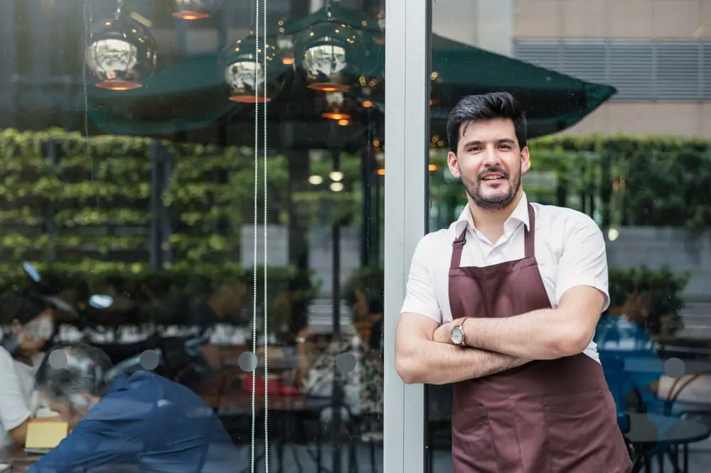 A cafe owner in the doorway of his own shop.